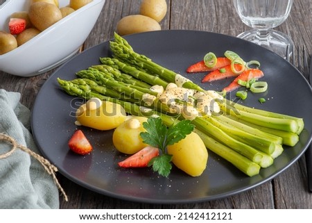 green asparagus, sauce and potatoes on a plate, fresh cooked meal