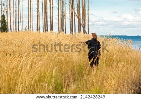 beautiful girl in a field on the shore of the sea and blue sky with clouds close-up