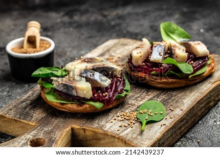 Herring fillet. sandwich with slices of pickled Atlantic herring fillet, beetroot salad, green spinach, onion, Scandinavian cuisine. banner, menu, recipe place for text, top view. Royalty-Free Stock Photo #2142439237