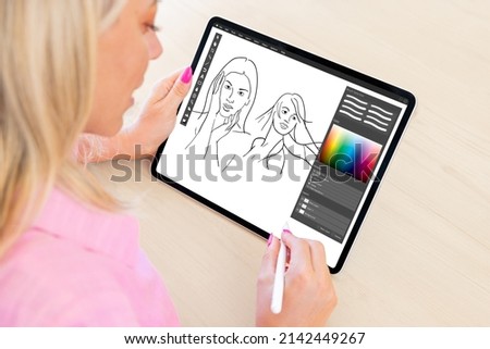 Woman drawing sketches with pencil on digital tablet computer