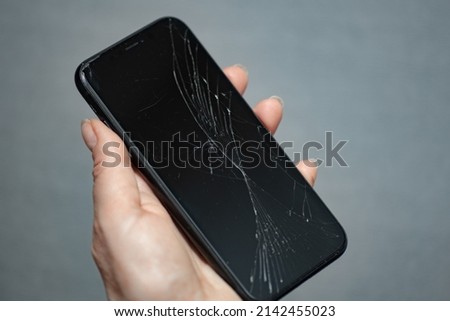 hand holding smartphone with cracked screen, gadget repair, selective sharpness