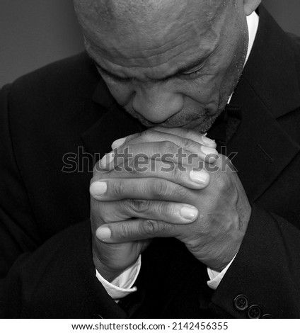 man praying to god with hands together on grey background stock photo 