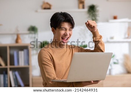 Asian man is smiling and expressing happy feeling on the computer laptop screen. young male got good news and show his cheerful face.Happiness men looking on laptop read message feel excited at home Royalty-Free Stock Photo #2142464931