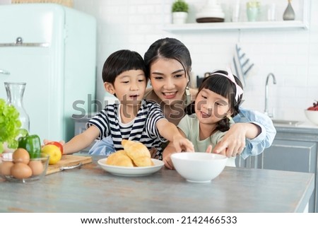 Happy Asian mother with son and daughter in kitchen. Enjoy family activity together.