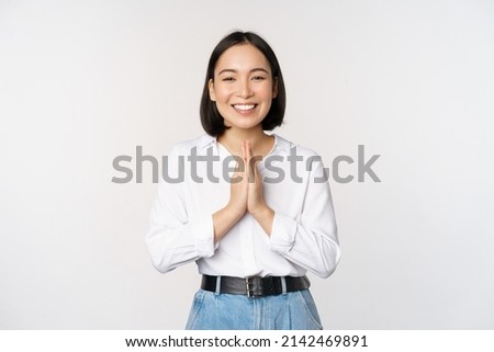 Portrait of happy asian girl laughing and smiling, showing thank you, namaste gesture, grateful for smth, standing over white background Royalty-Free Stock Photo #2142469891