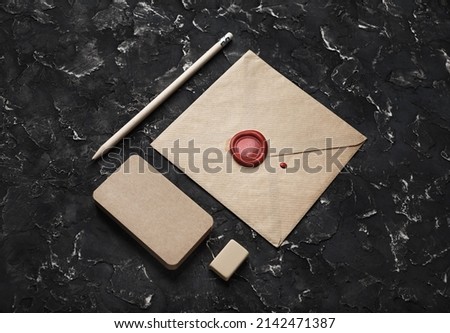 Photo of blank vintage envelope and stationery on black plaster background.