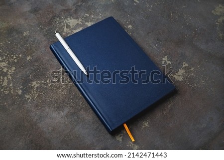 Blank notepad and pen on concrete background. Stationery elements. Template for placing your design.