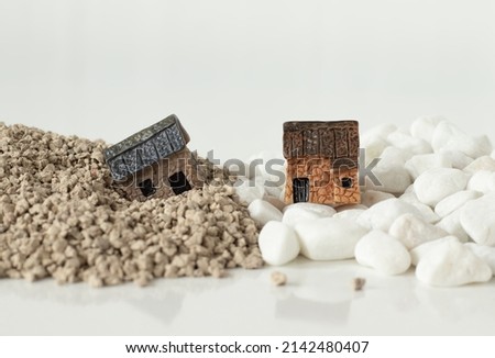 Two miniature houses, one built on a rock, and the other built on a sand isolated on white. Jesus Christ gospel parable. The biblical concept of faith and obedience to God. A close-up. Royalty-Free Stock Photo #2142480407