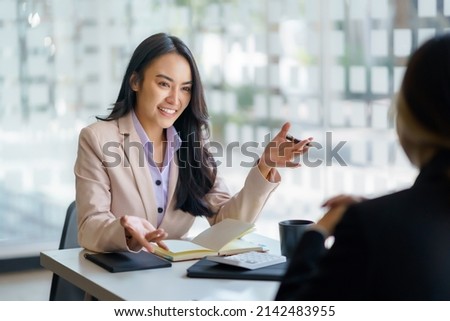 Two beautiful young Asian businesswoman in the conversation, exchanging ideas presentation analyze plan marketing and investment.