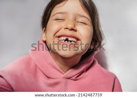 portrait of a beautiful emotional caucasian girl in a pink sweatshirt who lost her first tooth. Close-up of a child with a smile and joy Royalty-Free Stock Photo #2142487759