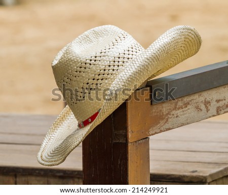 Hat hanging on a wood fence post on an agriculture farm field.