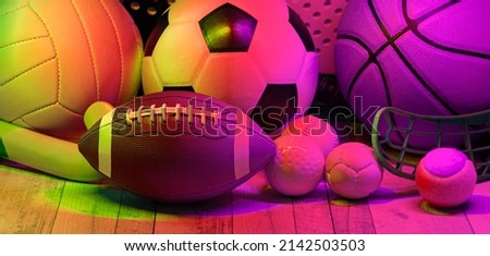 Sports equipment, rackets and balls on hardwood court floor with neon light background. Horizontal education and sport poster, greeting cards, headers, website
