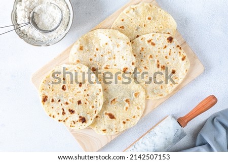 Recipe step 2. Homemade wheat tortillas, pita bread, tortilla, pita with ingredients for cooking on a white table. Top view. The concept of homemade food. Royalty-Free Stock Photo #2142507153