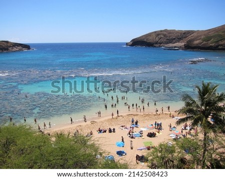 Hanauma Bay crater beach and coral reef, a popular tourist destination. Of volcanic origin, it is located at Hawaii, Oahu. People sunbathing, snorkeling and swimming. Blue sky, turquoise sea. 