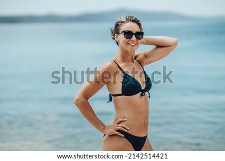 An attractive middle age woman is enjoying and posing on the beach.