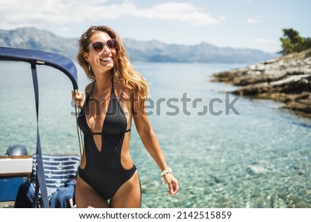 An attractive young woman spending the day on her private yacht near the beach.