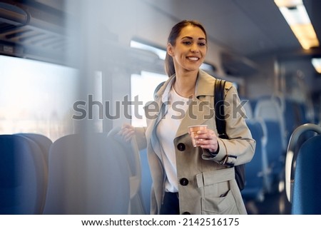 Happy woman enjoying in train ride while drinking takeaway coffee.  Royalty-Free Stock Photo #2142516175