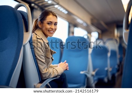 Young happy passenger enjoying on her journey by train and looking at camera. Copy space.  Royalty-Free Stock Photo #2142516179