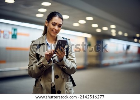 Young happy passenger text messaging on her cell phone at subway station. Copy space.  Royalty-Free Stock Photo #2142516277