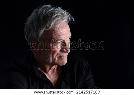 portrait of senior man looking away  on black background