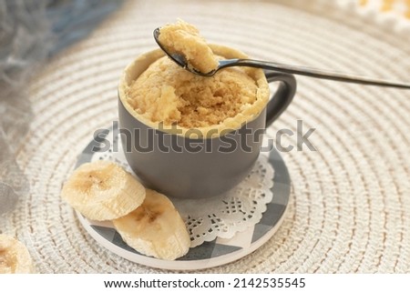 cupcake in a mug with banana pieces. Banana cupcake on a light background. vanilla biscuit in a mug. The concept of a dessert in the microwave. bananas cake. High quality photo Royalty-Free Stock Photo #2142535545