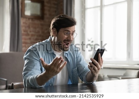 Excited smartphone user man staring at screen in surprise, reading text message getting good news, rejoicing at success, luck, happy opportunity, winning prize, gasping in shock, laughing, smiling Royalty-Free Stock Photo #2142535929
