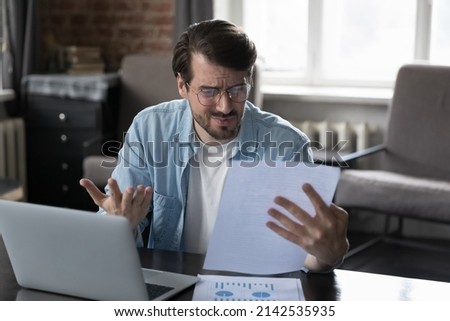 Annoyed frustrated entrepreneur man looking at paper report with bad news, getting problems, bankruptcy, financial loss. Businessman reading wrong document with mistake, rejection notice from bank