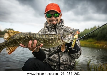 Fisherman and trophy Pike. Fishing background. Royalty-Free Stock Photo #2142541263
