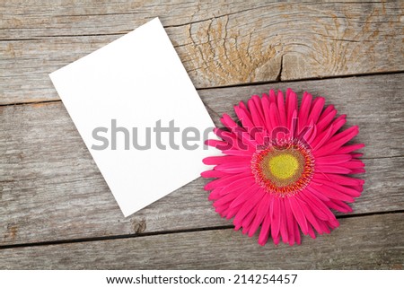 Photo frame and gerbera flower over wooden table background