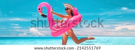 Beach travel funny woman happy having fun at luxury hotel vacation woman jumping of joy taking phone selfie with pink inflatable swimming pool mattress at overwater bungalow resort.