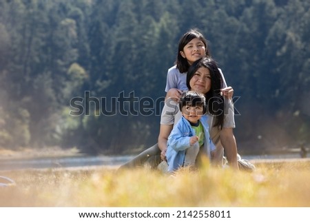 Mexican mother with daughter and son hugging outdoors