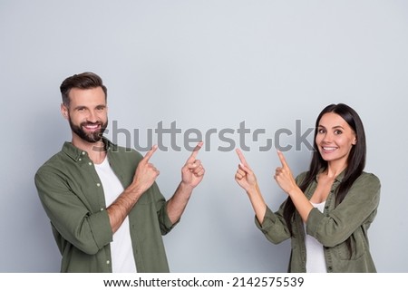 Portrait of attractive cheerful couple demonstrating copy blank empty space ad isolated over grey pastel color background