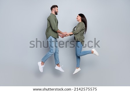 Full length profile side photo of romantic guy lady hold hands jump up isolated grey color background