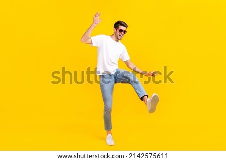 Full body photo of cool young brunet guy dance wear eyewear t-shirt jeans footwear isolated on yellow background Royalty-Free Stock Photo #2142575611