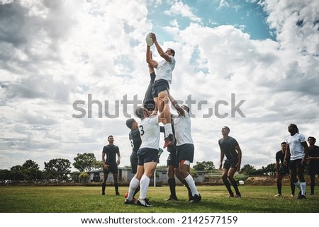 Reach for the sky. Shot of two rugby teams competing over a ball during a line out of a rugby match outside on a filed. Royalty-Free Stock Photo #2142577159