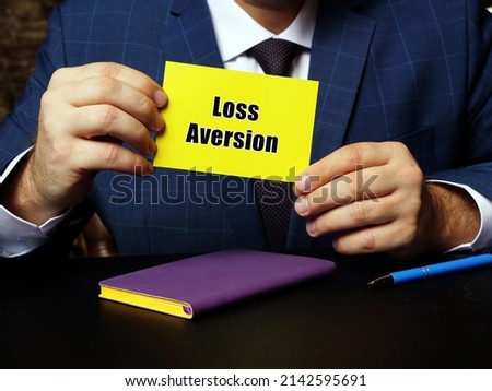 Blank yellow business card in a hand with phrase Loss Aversion . Horizontal shot.
 Royalty-Free Stock Photo #2142595691