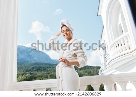 pretty woman in a white robe on the balcony bit on green nature unaltered