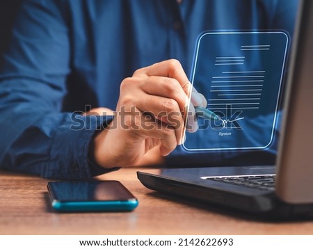 Electronic signature and paperless office concept. A businessman uses a pen to sign electronic documents on digital documents on a virtual screen. E-signing. Technology and document management Royalty-Free Stock Photo #2142622693