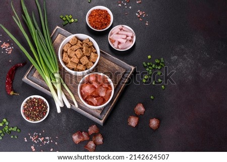 Dried meat slices with spices and herbs. Snacks for beer On a black stone background. Top view