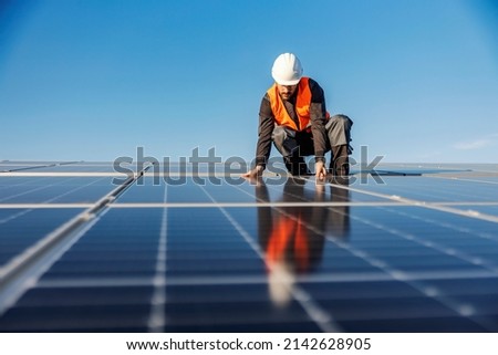 A worker installing solar panels on the roof. Royalty-Free Stock Photo #2142628905