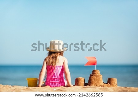 baby child in hat sits on beach against background of sea and plays sand, builds castle. vacation with kids in sunny summer. Royalty-Free Stock Photo #2142662585