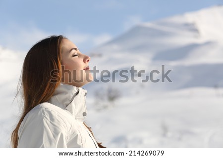 Profile of an explorer woman breathing fresh air in winter with a snowy mountain in the background