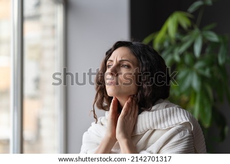 Young sick unhealthy woman covered in knitted plaid suffering from sore throat and swollen glands, feeling discomfort and pain when swallowing. Tonsillitis, laryngitis and lymph node inflammation Royalty-Free Stock Photo #2142701317