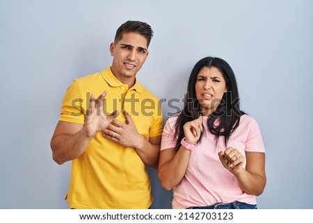 Young couple standing over isolated background disgusted expression, displeased and fearful doing disgust face because aversion reaction.  Royalty-Free Stock Photo #2142703123