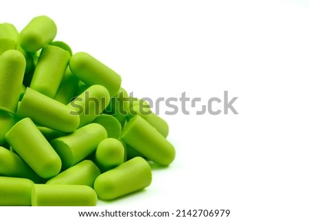 Lots of soft light green foam earplugs on a white background. Soft foam ear plugs. Copy space.Close-up.The concept of getting rid of noise in a loud place, hearing protection.High quality photo