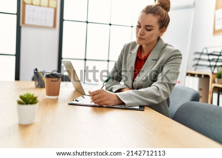 Young woman business worker writing on checklist working at office
