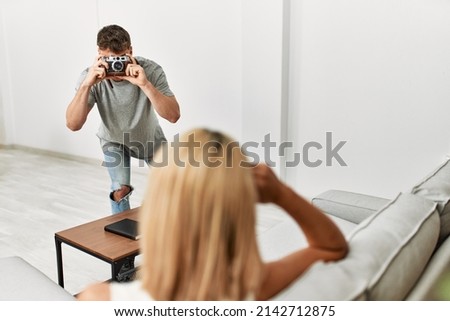 Man making photo to his girlfriend using camera at home.