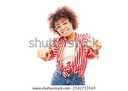 Portrait of friendly positive curly girl chooses you, points finger at the camera isolated on white background