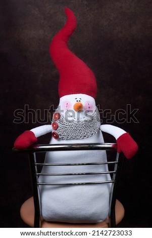 Soft toy snowman in a red cap on a chair