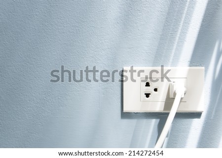 Power line and plug on the wall. Royalty-Free Stock Photo #214272454